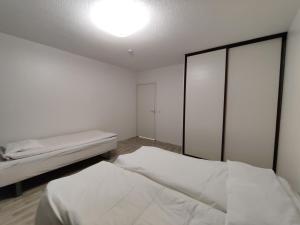 a white room with two beds and a light on the ceiling at Tilava kaksio 4 hengelle Nokialla in Tampere