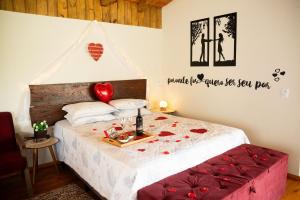 um quarto com uma cama com rosas vermelhas em Chalé Caminho do Sol em Rancho Queimado