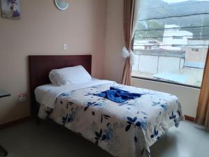 - une chambre dotée d'un lit avec une couverture bleue et blanche dans l'établissement Hostal Casa del Valle, 