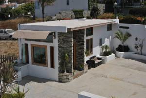 une maison blanche avec une terrasse couverte ornée de plantes dans l'établissement Casa de huéspedes Tuga, à Ensenada