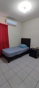 - un lit dans une chambre dotée d'un rideau rouge dans l'établissement Confortable habitación, à Colonia Alamitos