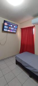Schlafzimmer mit einem Bett mit einem roten Vorhang und einem TV in der Unterkunft Confortable habitación in Colonia Alamitos