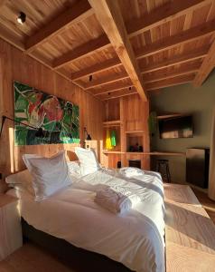 1 cama blanca grande en una habitación con techos de madera. en Cabanes avec jacuzzi les pieds dans la vignes, 