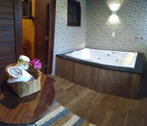 a bathroom with a tub and a basket of flowers at Pousada Sitio das Flores 12 km de Macacos Nova Lima in Nova Lima