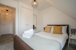 una camera da letto con letto, lenzuola e cuscini bianchi di ENTR - Modern Apartments in Windsor with Parking a Windsor