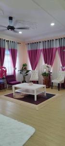 sala de estar con mesa blanca y cortinas moradas en Homestay Jari Manis, en Teluk Panglima Garang