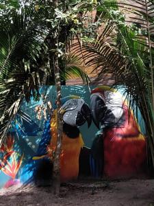a mural of two birds next to a palm tree at Morooka ÁGUA chalé com hidromassagem ALTER CHÃO in Alter do Chao