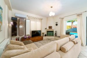 a living room with a large couch and a television at Athina Sea Villa Close To Athens in Oropós