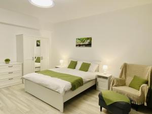 a white bedroom with a bed and a chair at GREEN STUDIO in Focşani