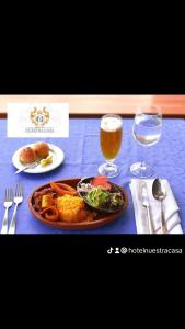 a table with a plate of food and two glasses of beer at Hotel Nuestra Casa Riobamba in Riobamba