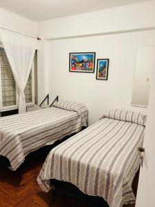 twee bedden in een kamer met witte muren bij Departamento Céntrico Tucumán 1B in San Miguel de Tucumán