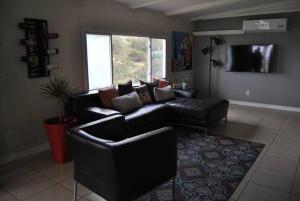 un salon avec un canapé en cuir noir et une télévision dans l'établissement Casa de campo en ruta del vino, à Villa de Juárez