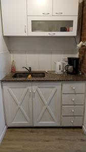 a kitchen with white cabinets and a sink and a counter at Cabaña a pasos del lago in Tandil +17 photos