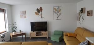 ein Wohnzimmer mit einem Sofa und einem Flachbild-TV in der Unterkunft L'étape in Mutzig