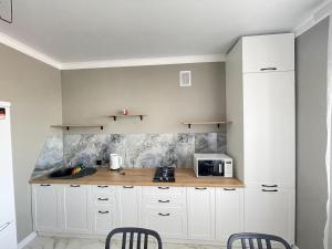 a kitchen with white cabinets and a counter with a microwave at # 22 Яркая и уютная квартира MODERN in Atyrau