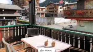 a table and chairs on a balcony with a view of a city at Appartement 2 chambres centre MORZINE in Morzine