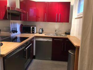 a kitchen with red cabinets and a sink at Appartement 2 chambres centre MORZINE in Morzine