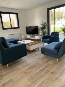 ein Wohnzimmer mit 2 blauen Sofas und einem TV in der Unterkunft Maison 8 pers 1 minute parc des expositions in Bohars