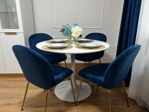 uma mesa com cadeiras azuis e uma mesa branca com pratos e flores em Florilor Residence II em Piteşti