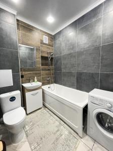 a bathroom with a toilet sink and a washing machine at # 22 Яркая и уютная квартира MODERN in Atyrau