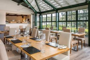 a restaurant with wooden tables and chairs and windows at Wharfe Lodge in Skipton