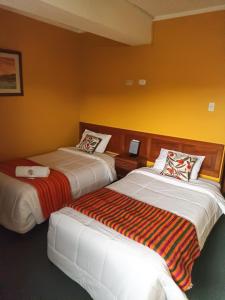 two beds in a room with yellow walls at Huaraz Center Hostal in Huaraz