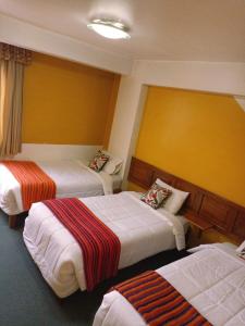 una habitación con 3 camas en una habitación de hotel en Huaraz Center Hostal, en Huaraz