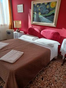 a bedroom with a large bed with red walls at Princess Guest House Canal View in Venice