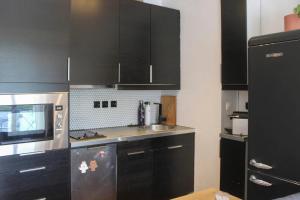 a kitchen with black cabinets and a microwave at Crossing cocoon with balcony and clear view in Paris