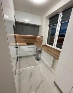 a kitchen with white cabinets and a window and marble floor at Apartmán v meste Michalovce in Michalovce