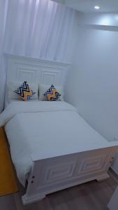 a white bed with two pillows on top of it at Cozy 2 bedroom apartment With gym &washer near yaya centre in Nairobi