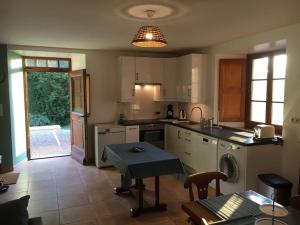 a kitchen with white appliances and a table in it at Maison confortable et calme, 2 chambres in Saint-Marcel-Bel-Accueil