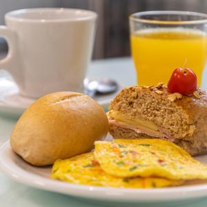 een bord met een broodje ei en een kop sinaasappelsap bij Hotel Negrini in Balneário Camboriú