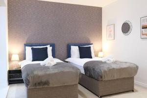 two beds in a hotel room with two pillows at Prime Location - 4 Bedroom 3.5 Bathroom House - Sleeps up to 8 - Free Parking, Fast Wifi, Balcony, Smart TV and Private Garden by Yoko Property in Milton Keynes
