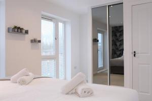 een witte slaapkamer met een spiegel en een bed bij Prime Location - 4 Bedroom 3.5 Bathroom House - Sleeps up to 8 - Free Parking, Fast Wifi, Balcony, Smart TV and Private Garden by Yoko Property in Milton Keynes