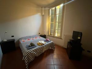 1 dormitorio con 1 cama con manta a rayas y ventana en AS APartment Modena, en Módena