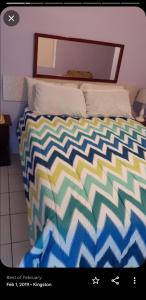 a bed with a colorful comforter in a bedroom at Cliff Apartment in Kingston