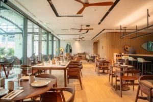 a restaurant with wooden tables and chairs and windows at EVOLUTION Cascais-Estoril Hotel in Estoril