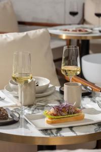 a table with two glasses of white wine and a sandwich at EVOLUTION Cascais-Estoril Hotel in Estoril