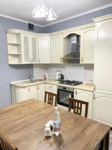 uma cozinha com armários brancos e uma mesa de madeira em # 268 Светлая и уютная квартира em Atyrau
