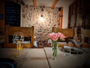 una mesa con dos copas de vino y un jarrón de rosas rosas en Auberge Saint Antoine, en Pelvoux