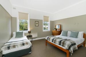 2 Betten in einem Zimmer mit 2 Fenstern in der Unterkunft Bundanoon Hotel in Bundanoon