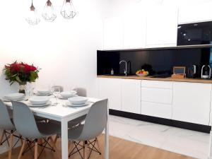 a white kitchen with a white table and chairs at Vista Residence Wola in Warsaw