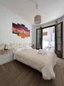 a white bedroom with a large bed and a window at Apartamentos Jardines de la Sitarilla in Granada