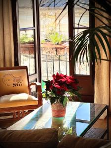 Habitación con mesa de cristal y jarrón con rosas rojas. en La Terraza de Porvenir 10 - Jerez de la Frontera, en Jerez de la Frontera