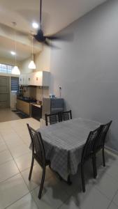 a dining room table with four chairs and a kitchen at Homestay Ara Kaseh in Mersing