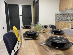 a wooden table with black plates and glasses on it at Le Baroque - plain-pied - 3 chambres - Wi-fi in Lens