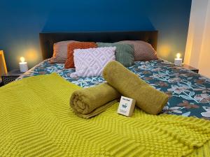 a bed with a yellow blanket and pillows on it at Le Baroque - plain-pied - 3 chambres - Wi-fi in Lens