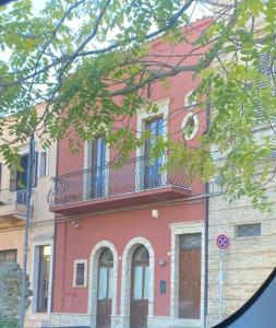 un bâtiment rose avec un balcon en haut. dans l'établissement RESIDENZA IN PIAZZETTA, à Vasto