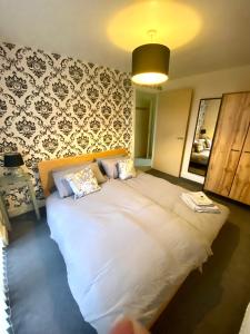a large white bed in a room with a wall at Lovely 2 bed apartment in Crosby in Liverpool